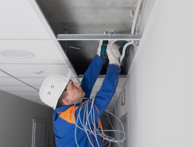 maintenance worker installing cables in office